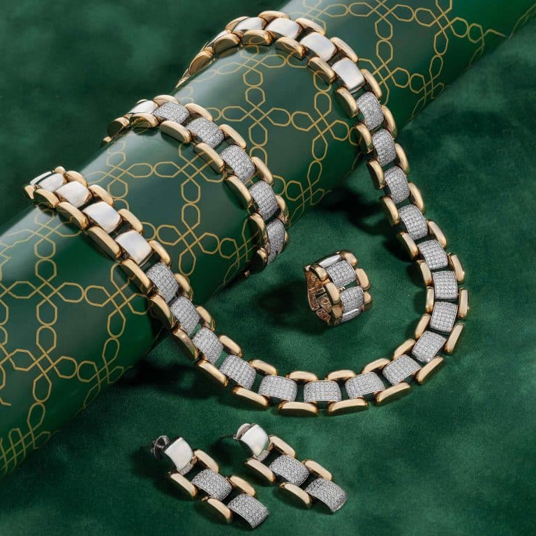 عکاسی تبلیغاتی زیورآلات طلا با الماس شامل دستبند، حلقه و گوشواره، چیده شده روی سطح مخمل سبز با پس‌زمینه الگوی تزئینی در استودیو ذوزنقه تبریز.
